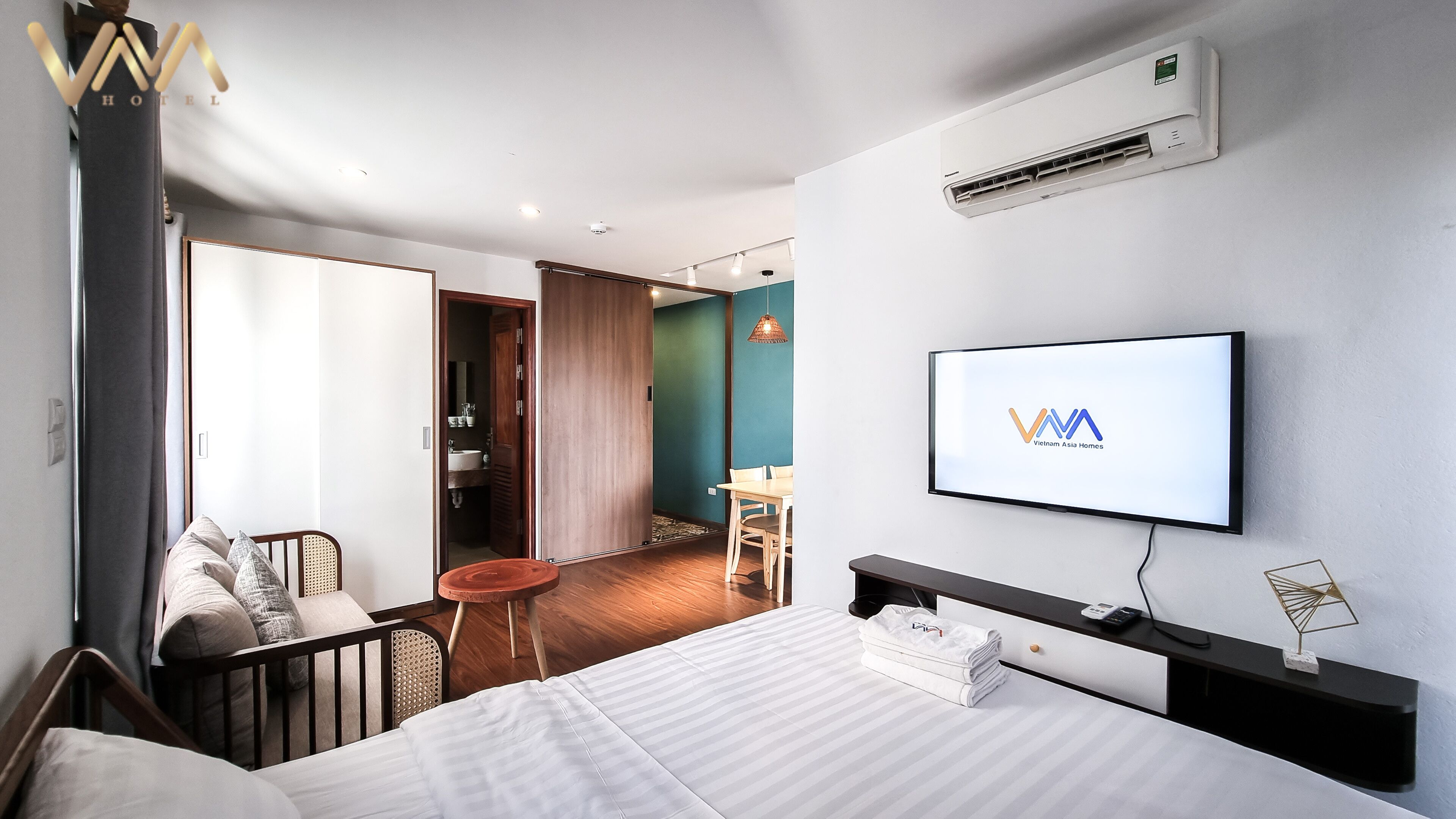A hotel room with a bed, a TV, a desk with a chair, and a bathroom visible through an open door.