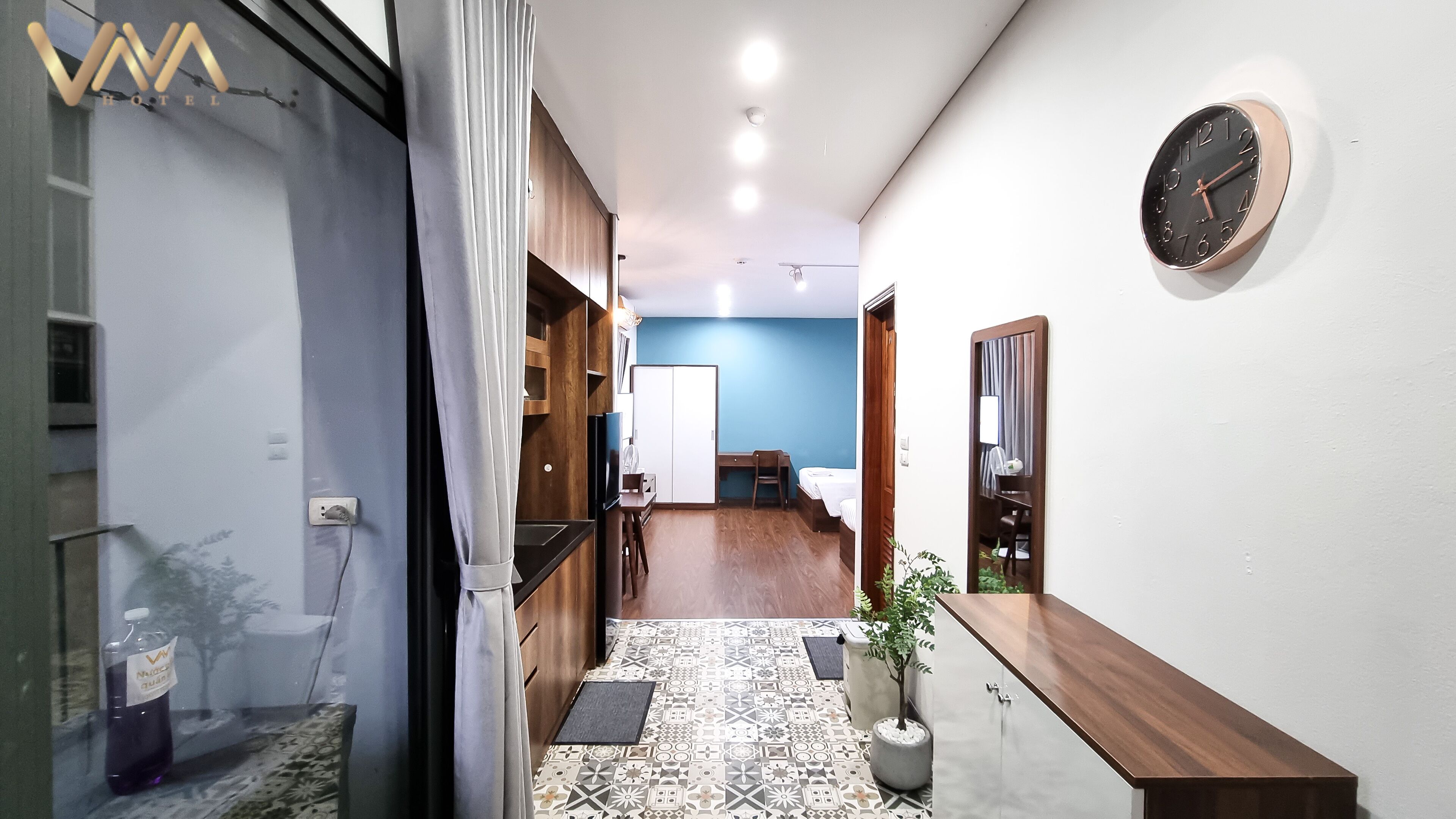 A hotel corridor with a wooden desk, a bed, and a blue wall.