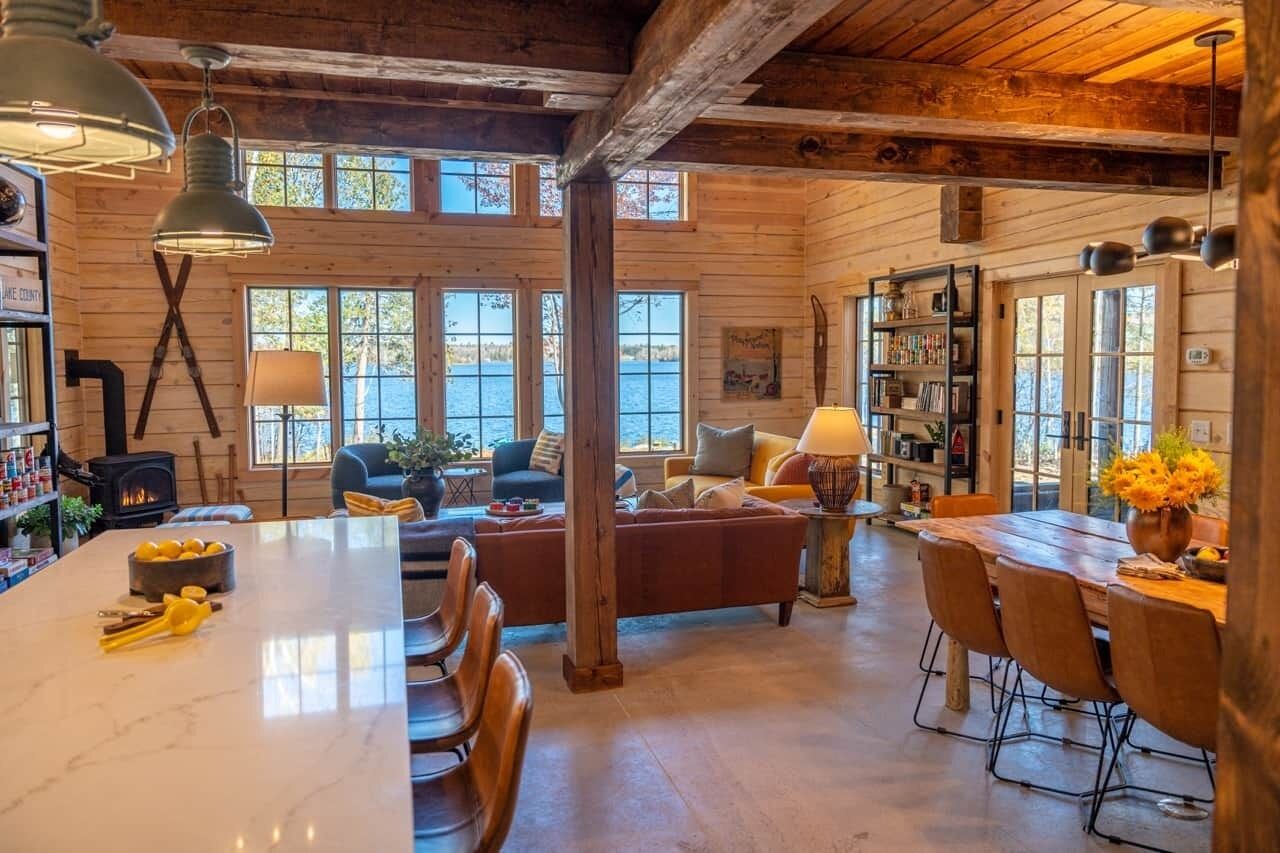 A spacious cabin interior with a large dining table, a cozy seating area, and a fireplace.