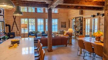 A spacious cabin interior with a large dining table, a cozy seating area, and a fireplace.