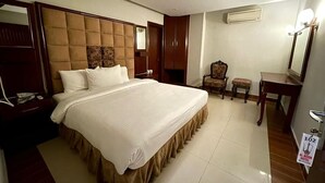 Habitación de hotel con una cama grande, un escritorio, una silla, un espejo y un cartel que indica el número de habitación 102.