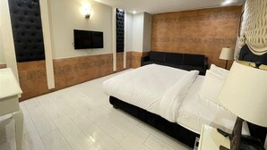 Un dormitorio moderno con una cama grande, un televisor de pantalla plana montado en la pared y un panel decorativo.