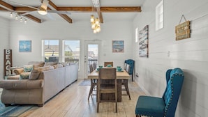 Een ruime woonkamer met een houten plafond, een eettafel en een bank.