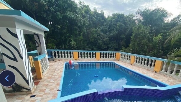 Una piscina rectangular con borde de azulejos, rodeada por un muro bajo con barandilla.