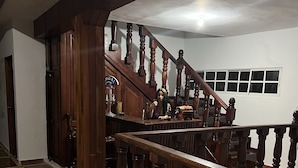 Un pasillo amplio con escaleras de madera y suelo de baldosas.