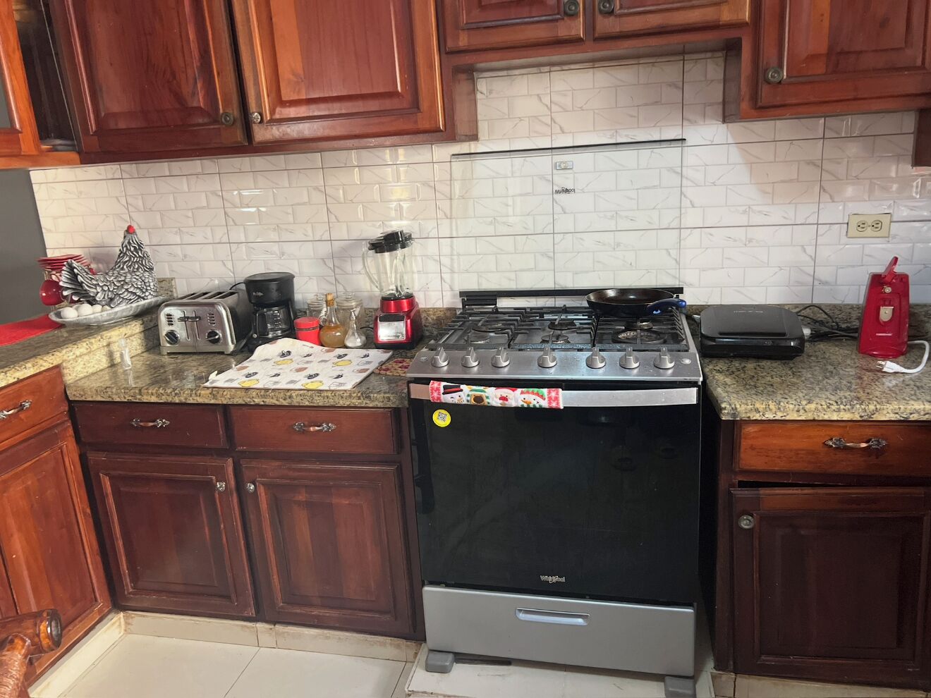 A kitchen with wooden cabinets, a gas stove, a microwave, and a toaster.