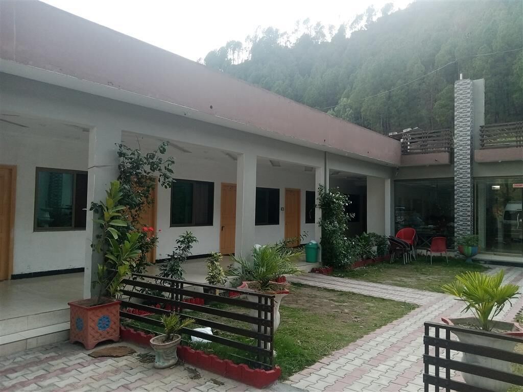 Un edificio con un espacio al aire libre cubierto, plantas en macetas y mesas con sillas.