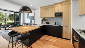 Une cuisine moderne avec des meubles en bois, un plan de travail noir et un îlot central doté de tabourets de bar.