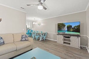 Un salon comprenant un canapé, une table basse, un téléviseur et un coin repas avec des chaises et une table.