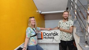 Two people standing by a reception desk with a sign for Dastak Hotels. - Dastak Hotels  (Islamabad)