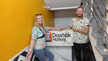 Two people standing by a reception desk with a sign for Dastak Hotels.