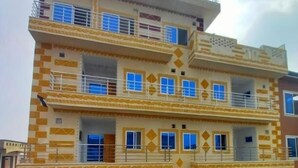 A multi-story building with a patterned facade, balconies, and a sign indicating a commercial use. - Dastak Hotels  (Islamabad)