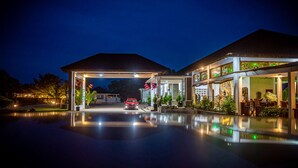 Un hôtel doté d’une entrée couverte, d’une piscine et d’un espace restaurant avec des places assises en plein air.