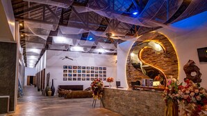 Un hall d’entrée spacieux avec un plafond haut, un comptoir d’accueil au design incurvé original et un mur orné de tableaux encadrés.