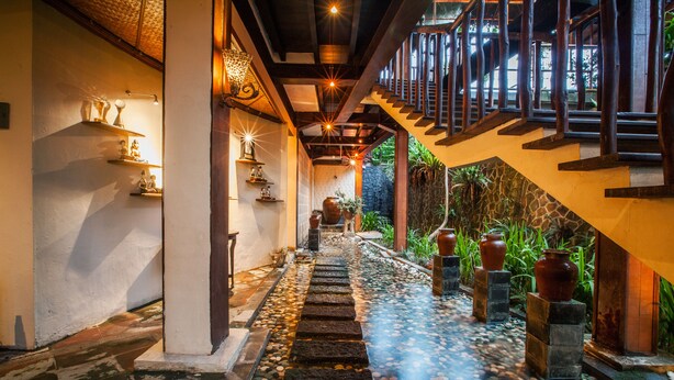 A stone pathway leading to a wooden staircase with a railing, surrounded by potted plants and decorative vases. - Dwaraloka Retreat Ubud (Ubud)