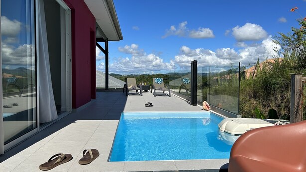 A rooftop pool with clear blue water, two lounge chairs, and a glass-enclosed area. - Villa Jalna grenadine with private pool in Martinique (Trois-Ilets)