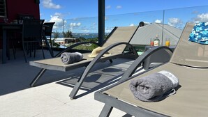 Una terraza en la azotea con sillones de descanso, una mesa y vista al mar.