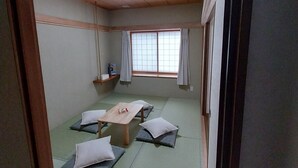 A traditional Japanese room with tatami mats, a low wooden table, and futon beds. - Miyuki Townhouse (Furano)