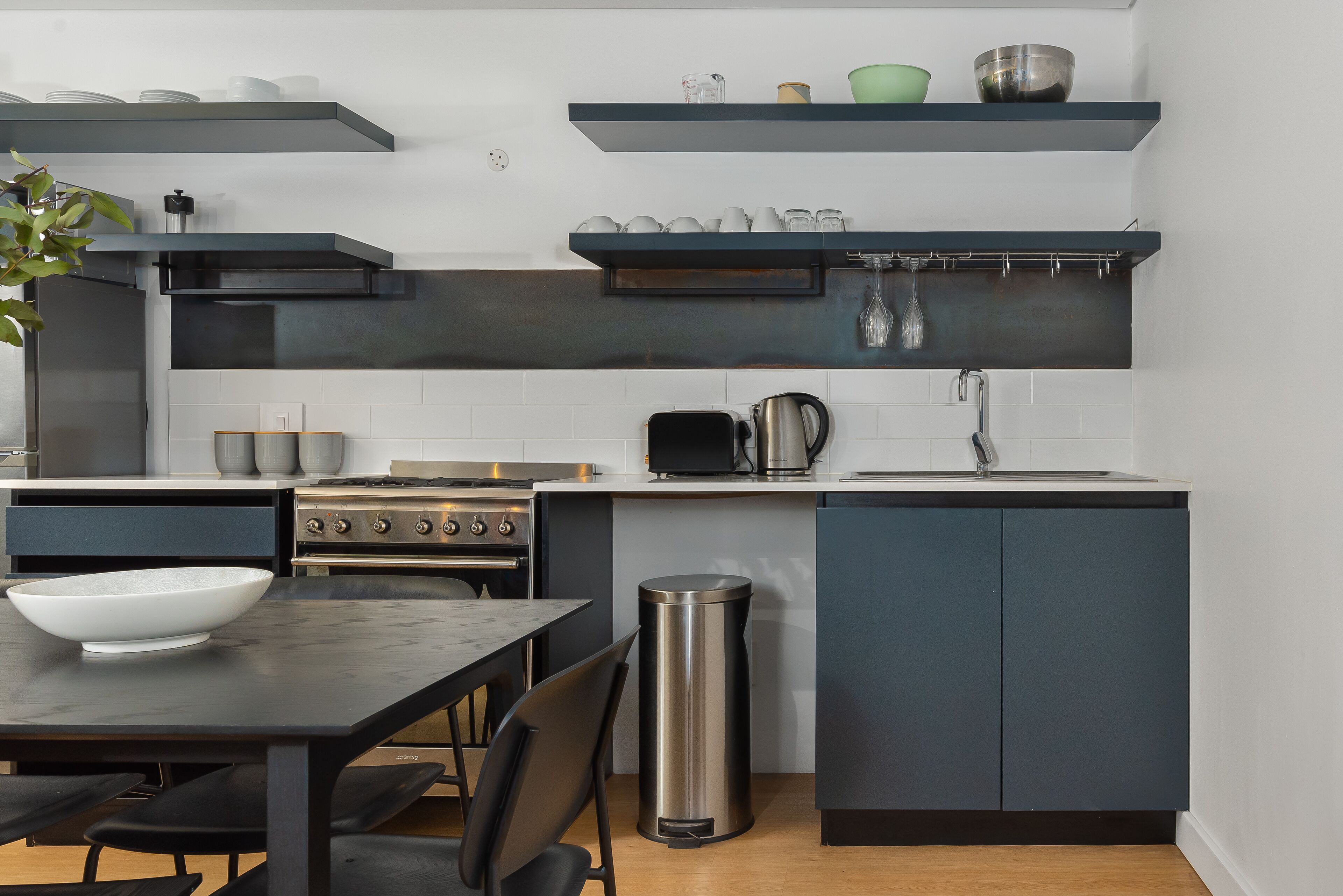 A modern kitchen with dark cabinets, a stainless steel stove, and a sink.