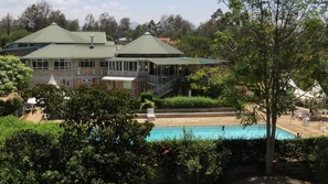 A large building with a swimming pool, surrounded by lush greenery and trees. - Thiiri Cultural center (Meru)
