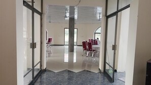 Un'ampia stanza con soffitto alto, grandi finestre e un pilastro centrale.
