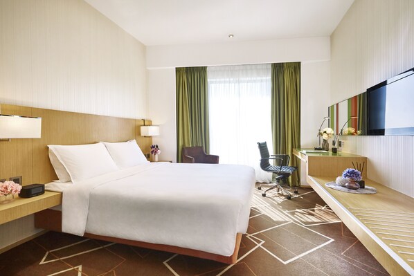 A hotel room with a large bed, a desk with a computer, a chair, and a TV mounted on the wall. - Vega Suites (Sai Kung)