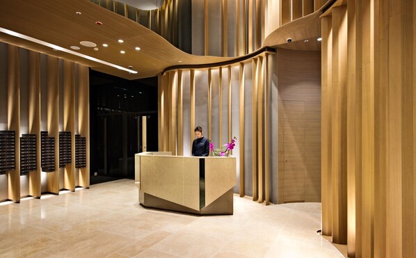 A modern reception area with a reception desk, vertical wooden panels, and a tiled floor.