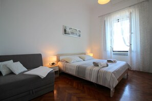 Ein Schlafzimmer mit einem Bett, einem Schlafsofa und einem Nachttisch mit Lampe.