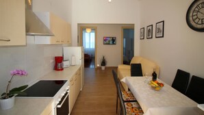Une cuisine compacte équipée d’une cuisinière, d’un évier et d’un coin repas avec une table dressée pour deux personnes.