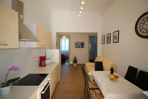 Una cocina compacta con estufa, lavamanos y comedor con una mesa lista para dos.