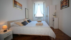Une chambre à coucher bien rangée, avec un lit, une table de chevet et une petite table d’appoint.