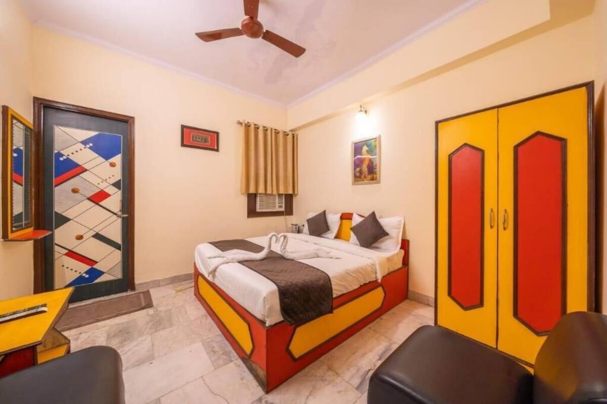 A bedroom with a bed, a desk, a chair, a wardrobe, and a ceiling fan.