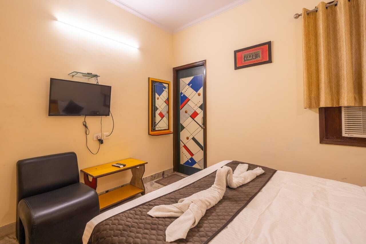 Una habitación de hotel con una cama, un televisor montado en la pared, un escritorio, una silla y una puerta con diseño geométrico.