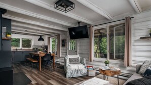 Een gezellig interieur in chaletstijl met een eethoek, een bank en een aan de muur bevestigde televisie.