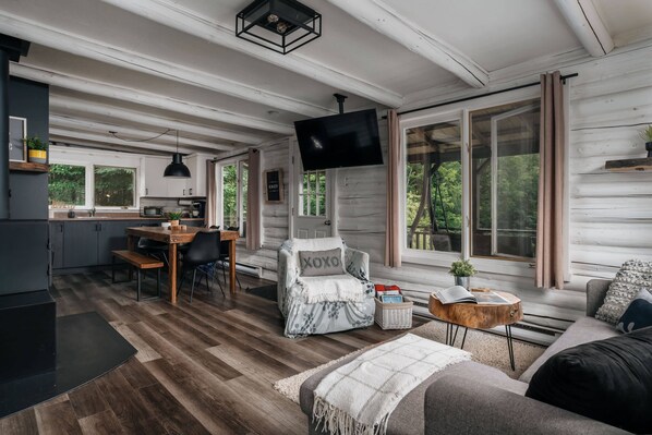En ombonad inredning i stugstil med ett matområde, en soffa och en tv som är monterad på väggen.