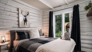 Een gezellige slaapkamer met een groot bed, een nachtkastje, een raam met gordijnen en een wanddecoratie.