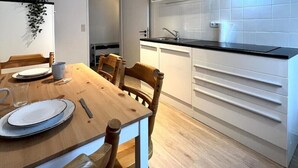 A modern kitchen with white cabinetry, a black countertop, and a stainless steel range hood. - Vacation apartment on a hillside with a picturesque view (Osterode am Harz)