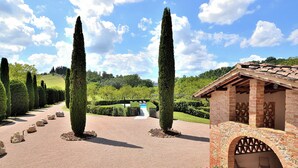 A landscaped garden with a brick building featuring an arched entrance and outdoor seating. - Entire Tuscan farmhouse with private pool between Siena and Florence (San Gimignano)