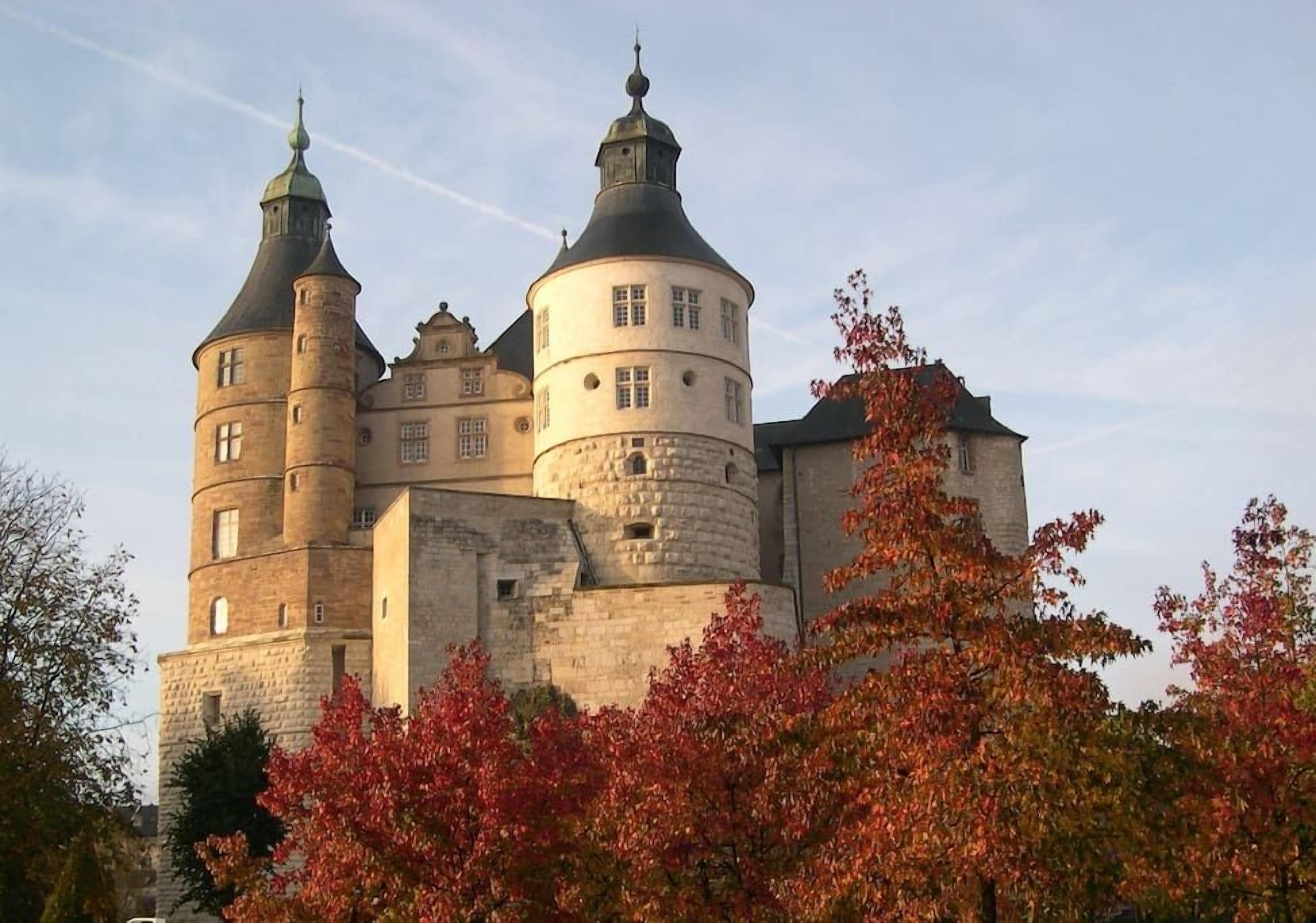 Un château historique doté de nombreuses tours, dont une tour centrale ronde particulièrement imposante.