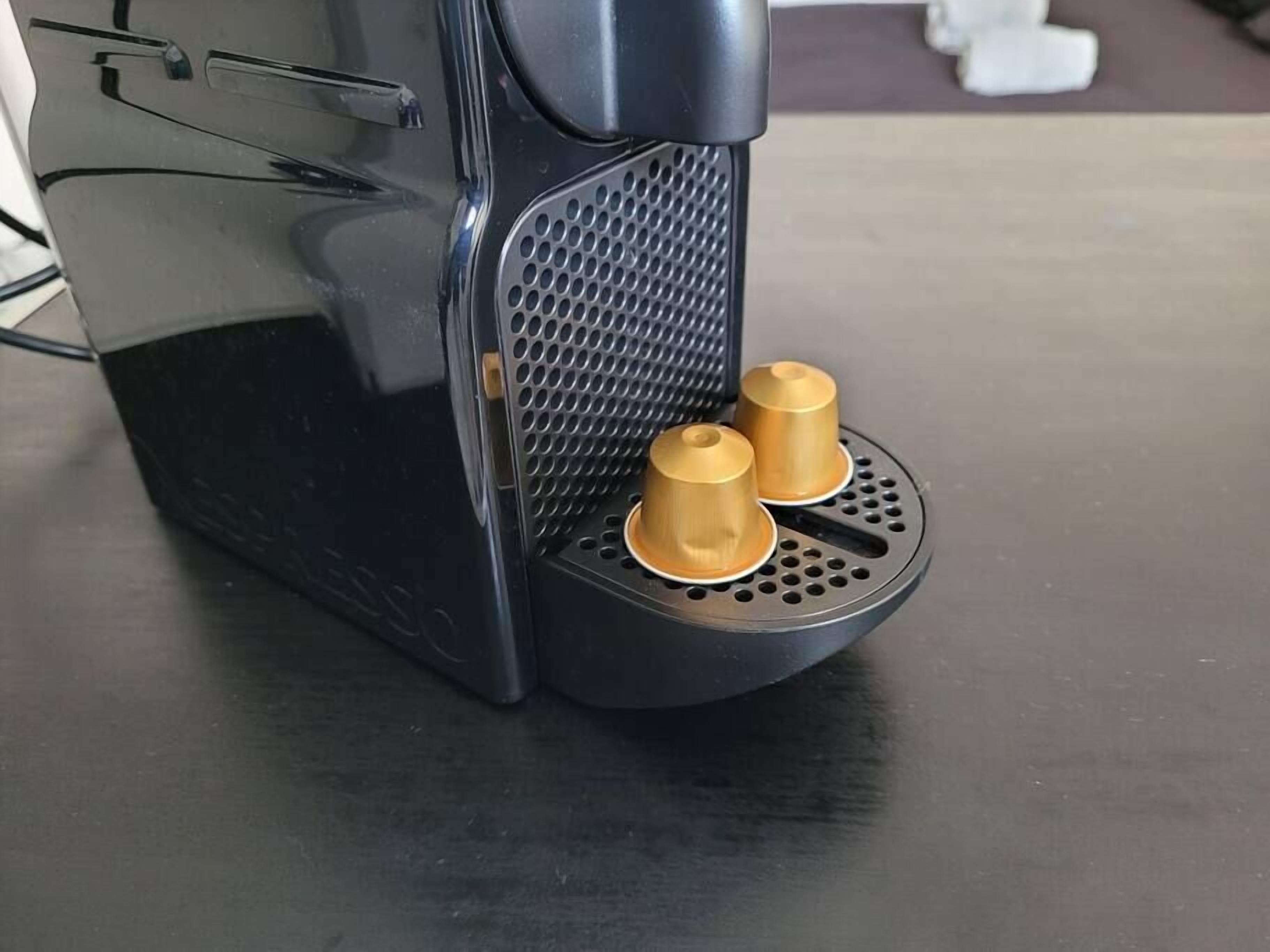 A coffee machine with two gold-colored cups on its drip tray.