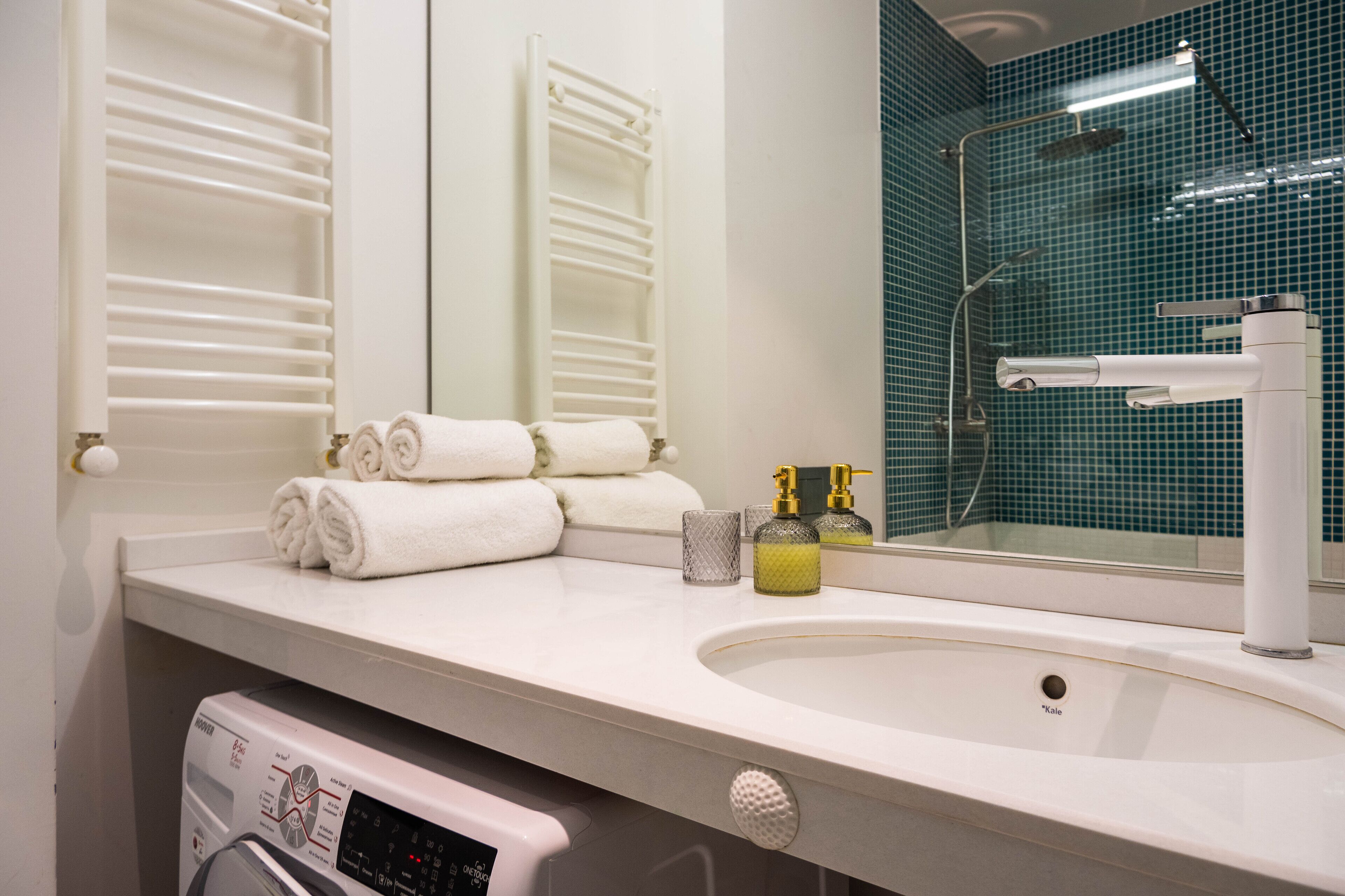 A bathroom with a white sink, a mirror, a towel rack, and a shower area.
