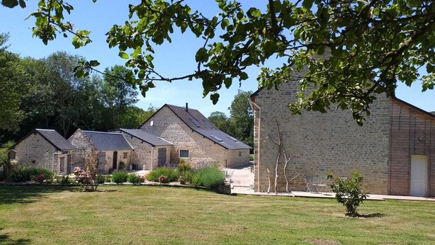 A row of stone buildings with pitched roofs, surrounded by a grassy area and trees. - Gîte Dune between orchard and Omaha beach (Colleville sur mer)
