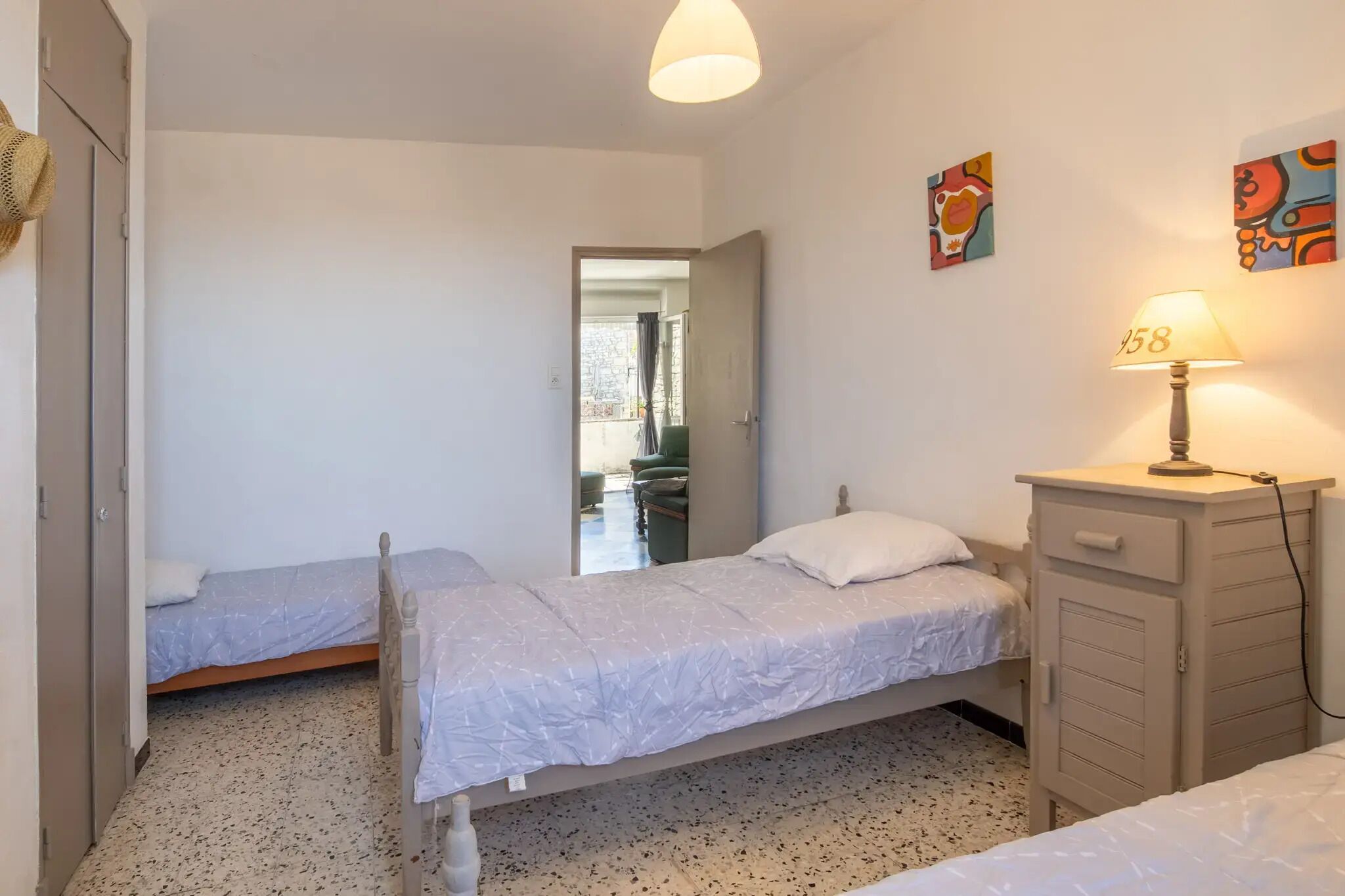 Ein Schlafzimmer mit zwei Einzelbetten, einem Kleiderschrank und einer Lampe.