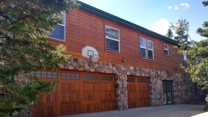 A two-story log cabin with a stone foundation, a basketball hoop, and a green door. - Location!  Nice log home in dark sky community next to several peaks (Westcliffe)