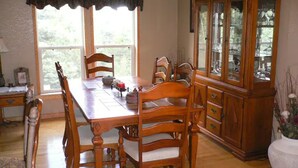 A dining room with a wooden table and chairs, a cabinet with glass doors, and a window with curtains. - Location!  Nice log home in dark sky community next to several peaks (Westcliffe)