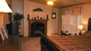 A bedroom with a bed, a fireplace, a ceiling fan, and a window with blinds. - Location!  Nice log home in dark sky community next to several peaks (Westcliffe)