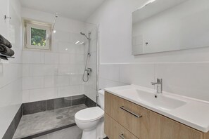 Une salle de bain moderne équipée d’une douche, de toilettes et d’un meuble-lavabo.