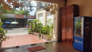 A hotel entrance with a Pepsi vending machine, potted plants, and a red mat on the floor. - CALI PHU QUOC HOTEL (Phu Quoc)