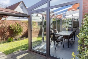 Enjoy outdoor dining in a patio with a glass door leading to a serene view of the surrounding neighborhood.