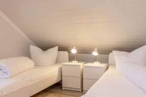 Cozy bedroom with two single beds, nightstands, and lamps.